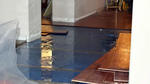 Hardwood boards pulled up from a floor and lying on plastic sheeting