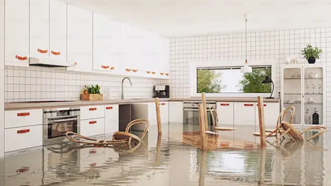 Bright kitchen with shallow water across the floor and chairs standing in it